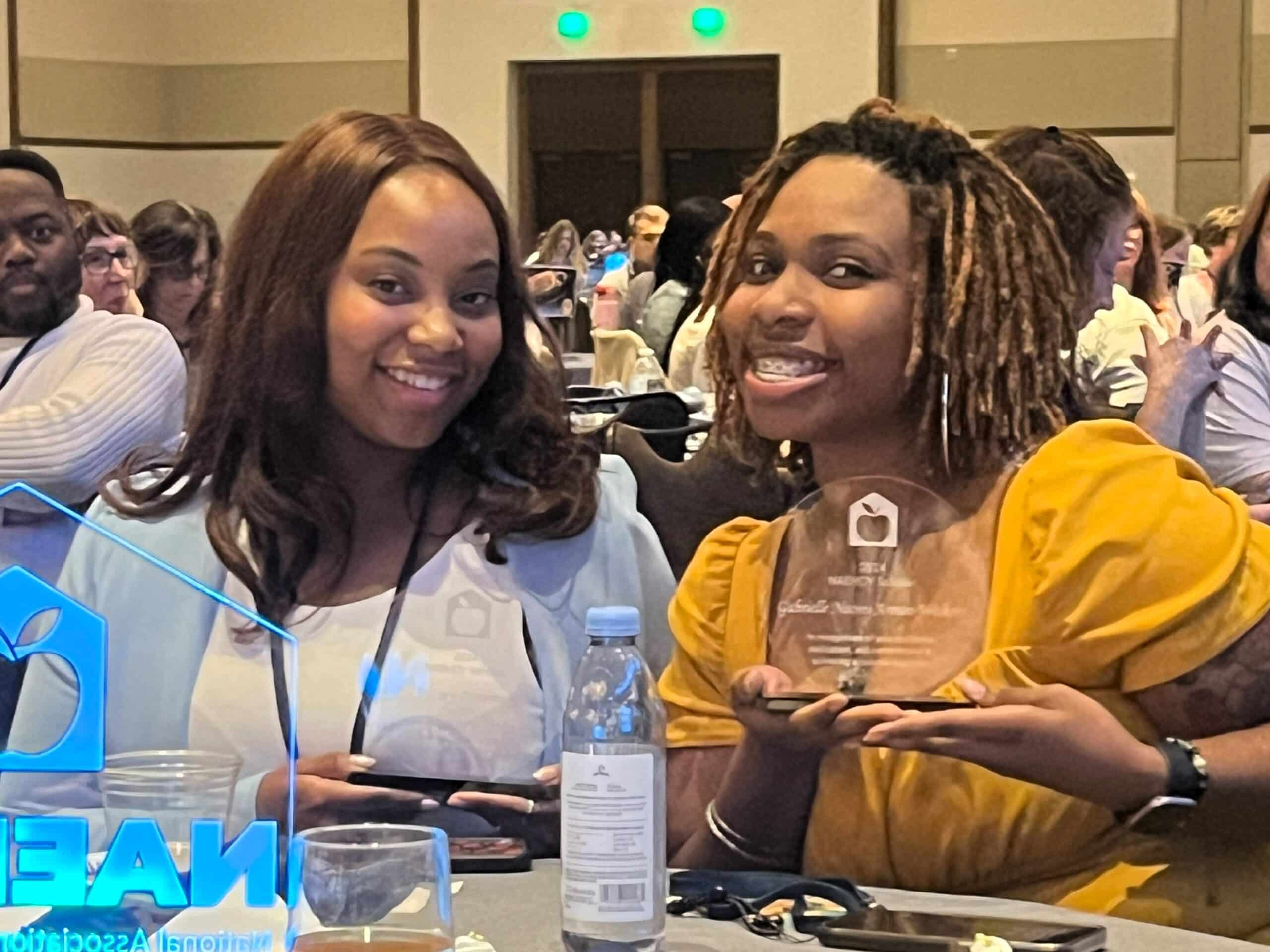 Two scholars holding award.